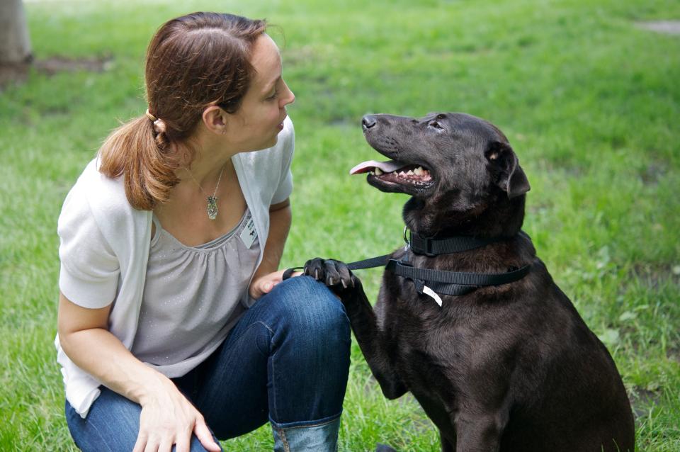 Woman crouching down next to black dog
